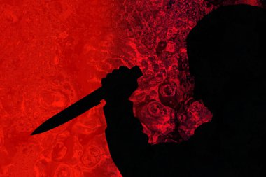 Koyu kırmızı ortamda bıçaklı bir adamın silüeti.