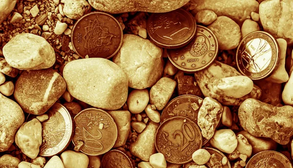 Taşların, sepya tonu imajının ve iş konseptinin ortasında avro sikkeleri