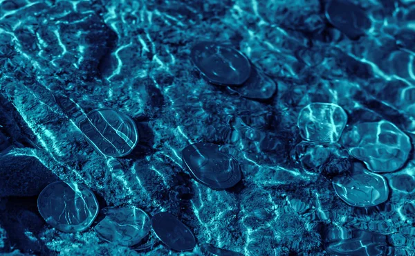 dark underwater euro coins in blue freshwater of the stream