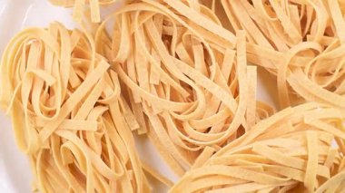 Tagliatelle 'in yuvaları, İtalyan çiğ yumurta makarna tabakası, beyaz tabakta, doğrudan avbove görüntüsü, dönen video.