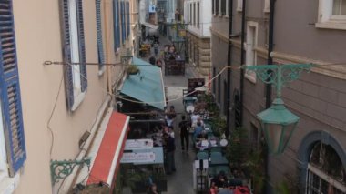 Cebelitarık. 22 Ekim 2022. Cebelitarık 'ta dar bir sokak manzarası. Restoran ve kafelerde yemek yiyen, geleneksel Akdeniz yemekleri yiyen insanlarla dolu..