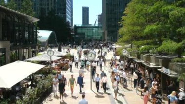 Canary Wharf, London, UK. 11th August 2022. Slow motion view of  people walking about Canary Wharf, enjoying the summer sunshine and outdoor dining.