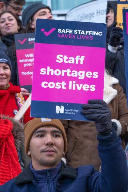 London, UK. 18th January 2023. Striking nurses holding placards and signs, demonstrating outside the main entrance of University College Hospital, London, in protest to government cuts and unfair pay.