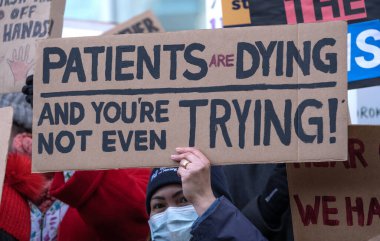 London, UK. 18th January 2023. Striking nurses holding placards and signs, demonstrating outside the main entrance of University College Hospital, London, in protest to government cuts and unfair pay.
