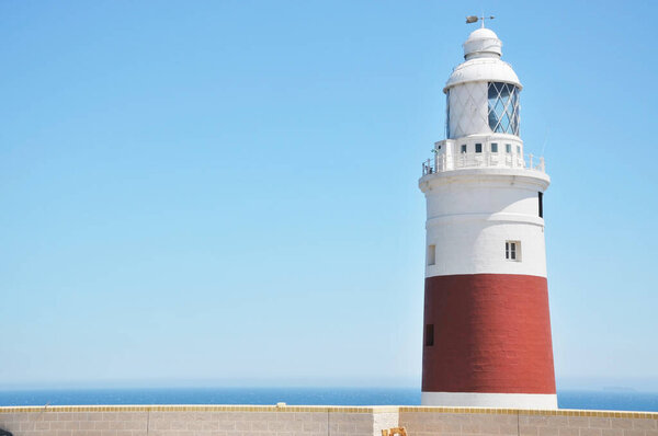 Маяк "Тринити" в мысе Европа в Джибриле на фоне ясного неба со Средиземным морем на заднем плане.