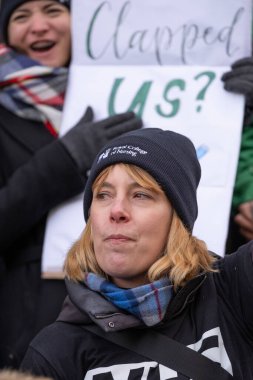 Striking nurses with placards and banners, demonstrating outside the main entrance of University College Hospital, London, in protest to government cuts and unfair pay.