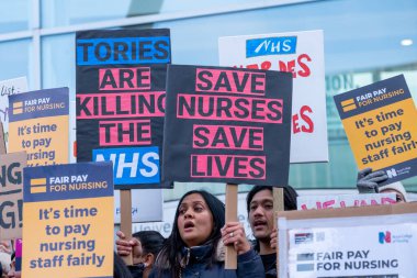 Striking nurses with placards and banners, demonstrating outside the main entrance of University College Hospital, London, in protest to government cuts and unfair pay.