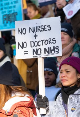 Striking nurses with placards and banners, demonstrating outside the main entrance of University College Hospital, London, in protest to government cuts and unfair pay.