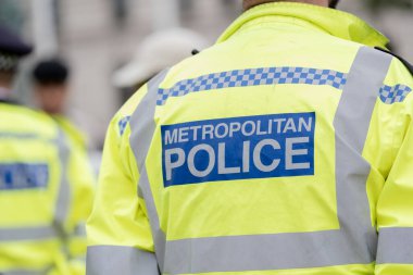 Londra, İngiltere. 19 Temmuz 2023. Londra 'nın merkezinde düzenlenen bir sokak gösterisine eşlik eden ve izleyen polis memurlarının giydiği yüksek görüşlü bir ceketin arkasında Metropolitan Polisi imzası var..