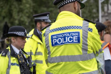 Londra, İngiltere. 19 Temmuz 2023. Londra 'nın merkezinde düzenlenen bir sokak gösterisine eşlik eden ve izleyen polis memurlarının giydiği yüksek görüşlü bir ceketin arkasında Metropolitan Polisi imzası var..