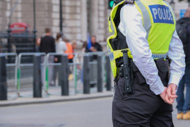 Londra, İngiltere. 23 Eylül 2023. Yüksek görüş mesafesi olan bir yelek giyen Metropolitan Polis memuru, Londra 'nın merkezindeki Downing Street yakınlarında düzenlenen bir sokak protesto gösterisine eşlik ediyor ve onları izliyor..