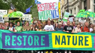 Londra, İngiltere. 22 Haziran 2024. Doğayı Yenile 'deki baş pankartın arkasındaki protestocular Londra' daki gösteriyi protesto ederek, doğa ve iklim acil durumları hakkında acil siyasi eylem çağrısında bulundular..