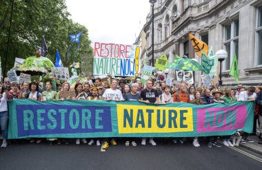 Londra, İngiltere. 22 Haziran 2024. Doğayı Yenile 'de pankartı olan çevre protestocuları Londra' da protesto gösterileri düzenleyerek, doğa ve iklim acil durumları hakkında acil siyasi eylem çağrısında bulundular..