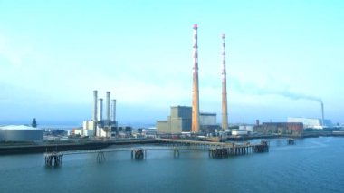 Dublin, İrlanda. 8 Eylül 2024. Sabahın erken saatlerindeki mavi gökyüzüne karşı Poolbeg Üretim İstasyonu 'nun yavaş hareket eden hava görüntüsü. İstasyon Dublin Limanı 'nın güney kıyısındaki Ringsend' de yer almaktadır..