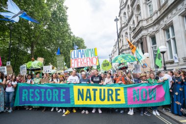 Londra, İngiltere. 22 Haziran 2024. Doğayı Yenile 'de pankartı olan çevre protestocuları Londra' da protesto gösterileri düzenleyerek, doğa ve iklim acil durumları hakkında acil siyasi eylem çağrısında bulundular..