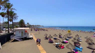 Playa De Las Americas, Tenerife, Kanarya Adaları. 8 Ağustos 2024. Playa de Las Americas 'taki altın kumlu plajın yükseltilmiş görüntüsü. Tatilciler güneşleniyor ve denizde yüzüyorlar.