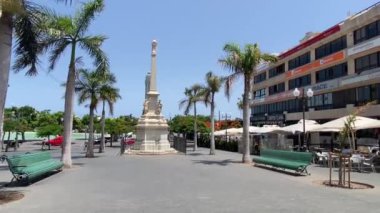 Santa Cruz, Tenerife, Kanarya Adaları. 7 Ağustos 2024. Palmiye ağacının geniş açılı manzarası Santa Cruz 'daki Plaza De La Candelaria' ya uzanır. Dükkanları, kafeleri ve restoranları berrak mavi bir yaz gökyüzüne sahiptir..