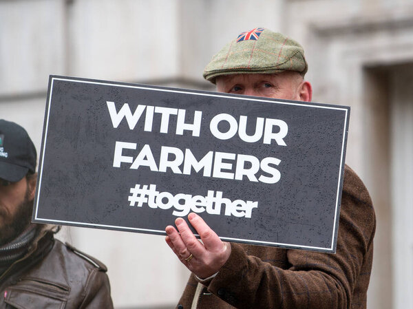 Лондон, Великобритания. 19 ноября 2024 года. Протестующий со знаком на Лондонском фермерском митинге в Уайтхолле, в знак протеста против планов правительства сократить льготу по налогу на наследство до 50% для ферм.