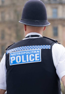 Londra, İngiltere. 6 Nisan 2024. Londra 'daki Trafalgar Meydanı' nda görev yaparken kask ve çelik yelek giyen bir Metropolitan Polisi 'nin arka görüntüsü..