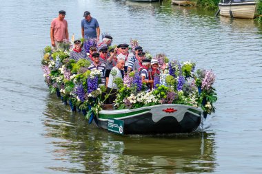 SCHIPLUIDEN, NETHERLANDS - 23 Haziran 2023: Geleneksel renkli çiçek ve sebze kanalı geçit töreni neşeli giyinmiş ve dans eden insanlarla süslenmiş tekneler. Varend Corso adında bir geçit töreni.