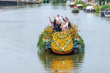 SCHIPLUIDEN, NETHERLANDS - 23 Haziran 2023: Geleneksel renkli çiçek ve sebze kanalı geçit töreni neşeli giyinmiş ve dans eden insanlarla süslenmiş tekneler. Varend Corso adında bir geçit töreni.