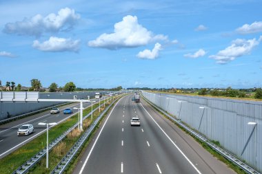 DELFT, NETHERLANDS - 31 Ağustos 2023: modern derin otoyol A4, öğleden sonra trafik yönü Lahey. Hollanda, Delft ve Rotterdam arasındaki doğal rezerv boyunca uzanan otoyol.