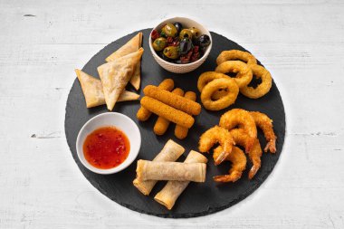 Büyük bir tabak bira çerezi. Zeytinler, börekler, kızarmış mozarella çubukları, çıtır kalamar halkaları, karidesler ve tatlı acı biber sosu.