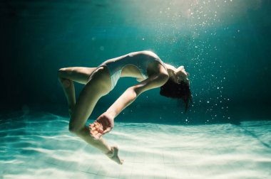 Underwater woman portrait in swimming pool at night. Dreamlike image. clipart