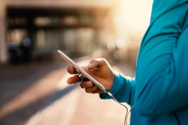 Güneşli bir günde dışarıda akıllı telefon tutan Afrikalı genç bir kadının detaylarını kapatın..