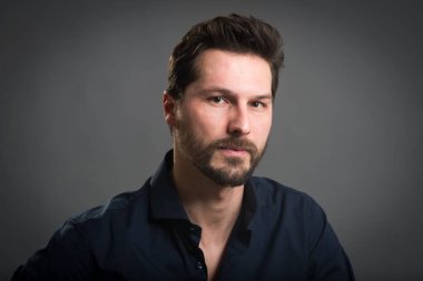 Kendine güvenen gülümseyen adam, karanlık arka planda portreyi kapat..