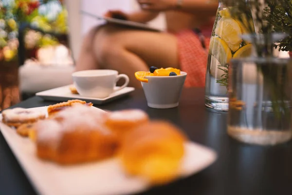 背景に女性とテラスで果物やお茶とおいしい朝食 畑の浅い深さ — ストック写真