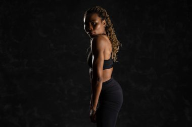 Siyah arka plana karşı, kendinden emin, genç, siyah Afrikalı bir kadın..