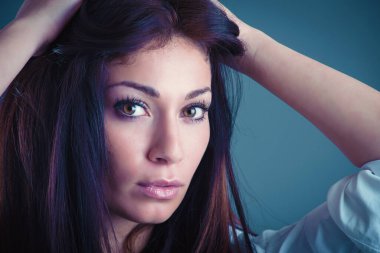 Güzel kendine güvenen genç kadın stüdyo mavi arka plan karşı portre kadar yakın.