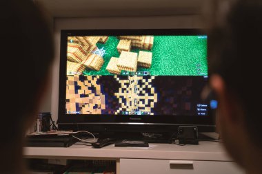 BOLOGNA, ITALY - 2020 Mart: genç kardeşler evde Playstation ile Minecraft video oyunları oynuyorlar. Minecraft, Notch olarak da bilinen oyun tasarımcısı Markus Persson tarafından yaratılan bir video oyunudur..