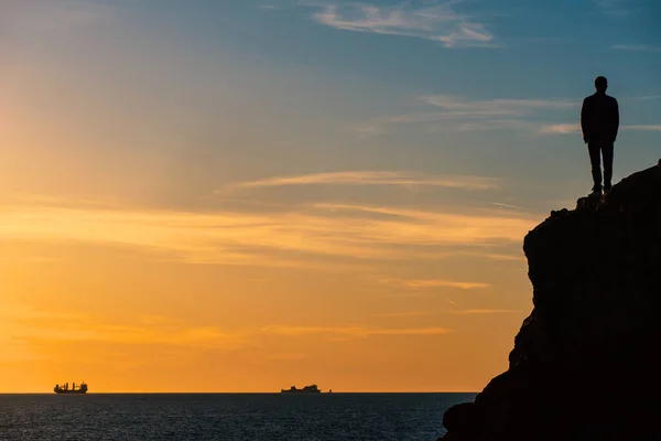 Gün Batımında Denizin Önündeki Bir Kayanın Üzerinde Duran Insan Silueti — Stok fotoğraf