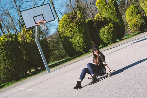 Genç Bir Kadın Basketbol Sahasında Kaykayın Üzerinde Oturuyor — Stok fotoğraf