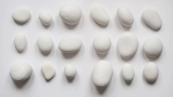 Stock image White pebblestones abstract composition. Top view on white background.