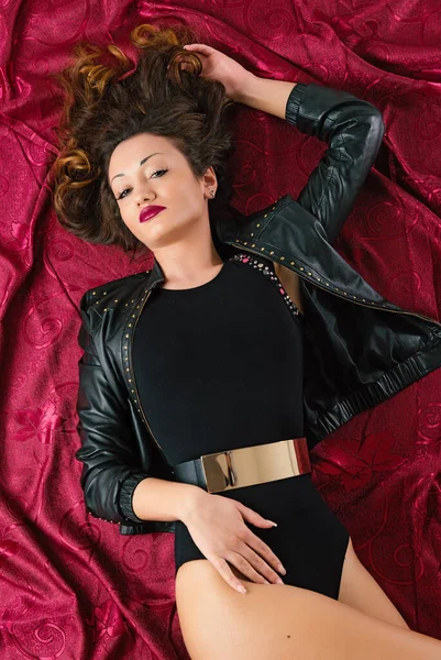 性感女人的肖像躺在地板上 背景是深红色面料 演播室图像 — 图库照片