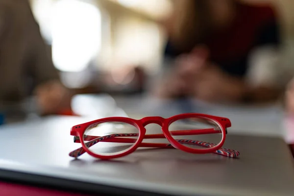 电脑笔记本电脑上的红色镜框眼镜在图书馆内的视野非常浅 学习概念 — 图库照片