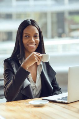 Milano'da açık havada kahve içerken dizüstü bilgisayarla çalışan gülümseyen iş kadını.