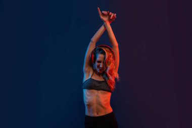 Duyarlı sarışın kadın stüdyo resmi ve kulaklıklar. Renkli jel fotoğrafçılık.