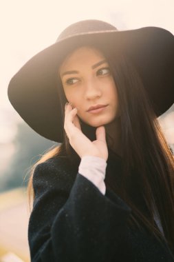 Beautiful woman portrait outdoors in a park wearing a vintage hat.