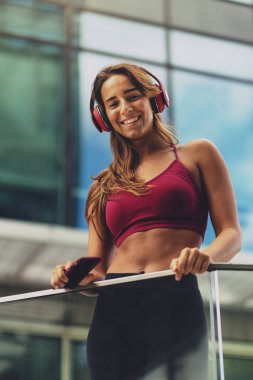 Şehirde kulaklıkla müzik dinleyen mutlu ve güzel bir kadının portresi. Yaşam tarzı konsepti, gençlik, eğlence, hayatın tadını çıkar.