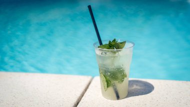 Sıcak ve güneşli bir günde yüzme havuzunun yanında taze Mojito kokteyli. Yaz mevsiminde rahatlama ve hayattan zevk alma kavramı.
