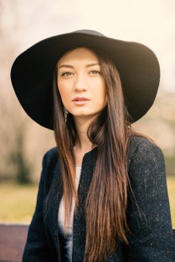 Beautiful woman portrait outdoors in a park wearing a vintage hat.