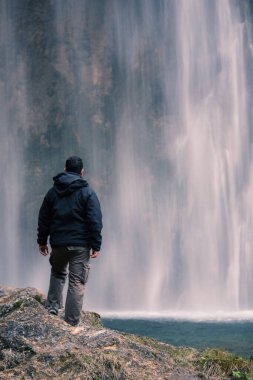 Plitvice Gölleri Ulusal Parkı 'ndaki şelaleye bakan adam. Hırvatistan. Avrupa. Vahşi doğayı keşfetme kavramı.