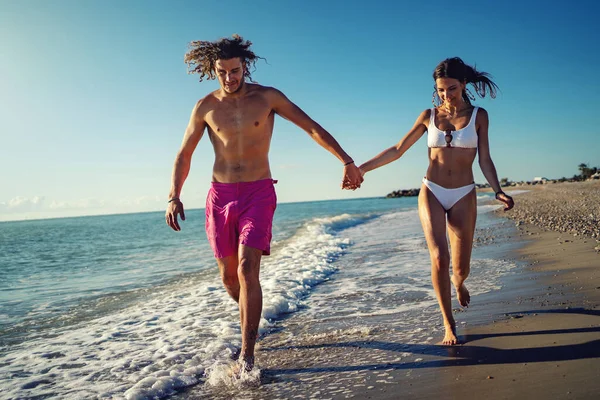 年轻而浪漫的情侣们在海滩上奔跑和玩乐 — 图库照片