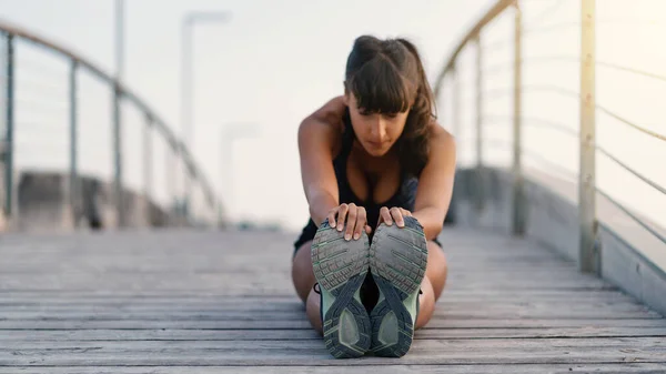 年轻的女运动员在一座桥上做着户外伸展的肖像 浅露深浅的田野 专注于鞋子 — 图库照片