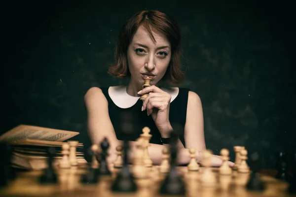 漂亮的红头发女人在深色背景下下下下棋 后期制作中添加的旧电影效果 — 图库照片
