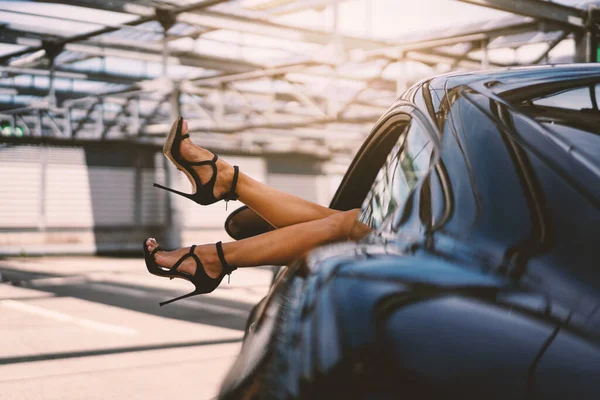 穿着高跟鞋的性感优雅女人的腿比黑色跑车更好看 — 图库照片